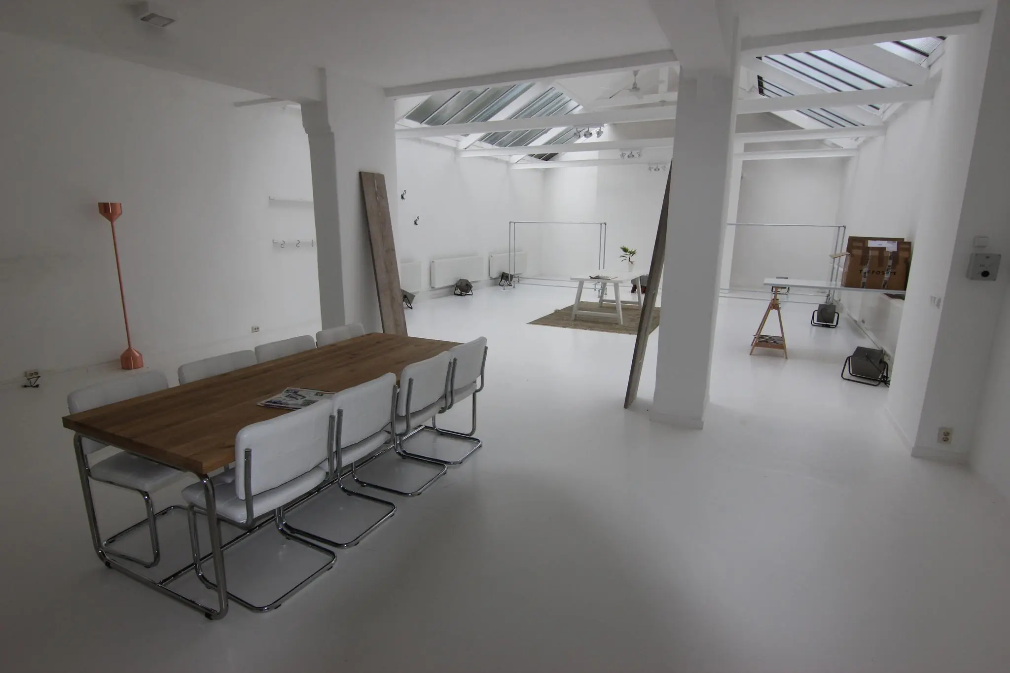 Lichte, moderne ruimte aan de Graaf Florisstraat met een houten vergadertafel, witte stoelen en grote dakramen.